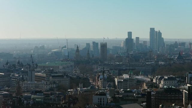 Aerial survey revealing the historic Palace of Westminster, iconic Elizabeth Tower, and modern skyscrapers of Vauxhall on a hazy day in London, United Kingdom