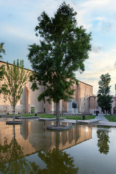 View of placid waters mirroring the warm hues of the building and verdant trees under a serene sky, a tranquil scene, Parma, Emilia Romagna, Italy.