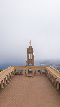View of the Santa Cruz Chapel stands tall, its stone facade bathed in the soft light filtering through the misty sky in Oran, Algeria.