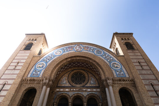 View of a grand cathedral with intricate mosaics and towering twin spires reaches towards the clear, sun-drenched sky, its facade a testament to architectural grandeur, Oran, Algeria.