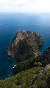 View of rugged cliffs meet the deep blue sea, where verdant vegetation clings to the steep slopes, creating a striking contrast in Bejaia, Algeria.