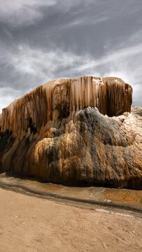 View of cascading mineral deposits create a striking contrast against the moody sky, showcasing nature's artistry in a serene landscape, Annaba, Algeria.