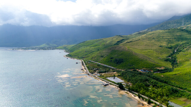 Aerial view of the tranquil lagoon meets the lush, green hills under a soft, cloudy sky, tt. Lang Co, Hue, Vietnam.
