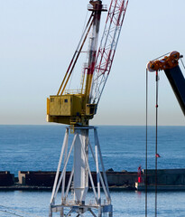 Fototapeta premium Yellow port crane on the quay with breakwater in the background