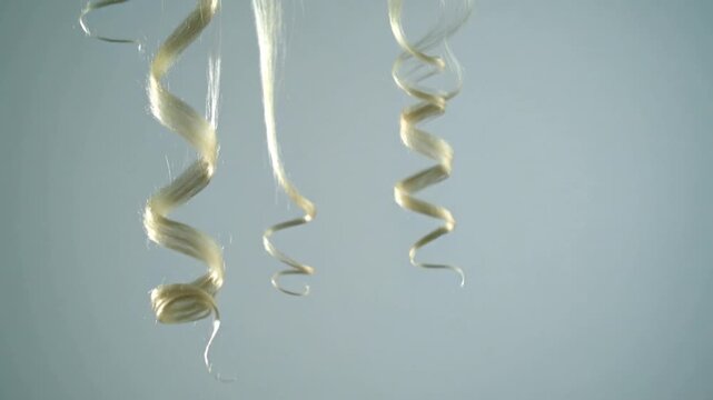 Cream lint-curl overlay with slight uncoiling, short downward drift, and soft disappearance near the upper left