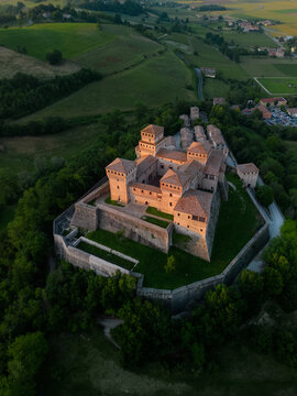 Aerial view of the majestic Torrechiara Castle, a fortress of stone and history, stands proud against a backdrop of rolling hills, Parma, Emilia Romagna, Italy.