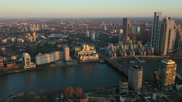 Warm sunset light illuminating MI6 Building and Vauxhall Bridge over River Thames with sprawling urban landscape of London and iconic skyline stretching into the horizon