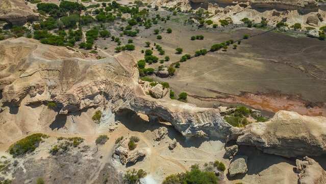 Aerial view of rugged, sun-baked earth and rocky formations where the desert meets the sea, sculpted by time and tide, Namibe, Angola.