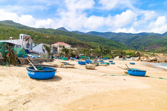 Bai Xep Beach, Vietnam - 30 January 2026: View of coracle boats resting on the golden sands of Bai Xep beach, beneath the vivid blue sky and rolling green hills.