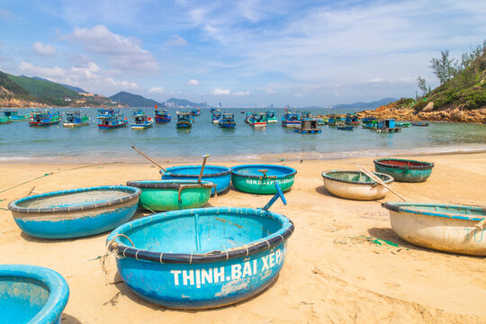 Quy Nhon, Vietnam - 30 January 2026: View of vibrant blue coconut boats resting on the golden sands of Bai Xep Beach, under a vast, cloud-streaked sky.