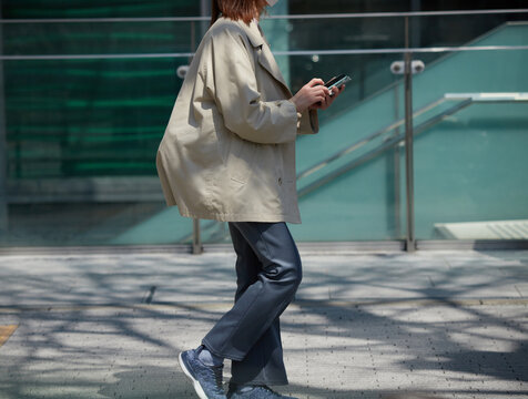 昼の都市の繁華街で歩きスマホの女性の姿