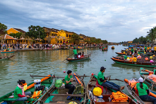 Hoi An, Vietnam - 28 January 2026: View of the lantern-lit bridge reflecting shimmering light onto the water, as boats glide gently through the river, carrying passengers past the ancient town.