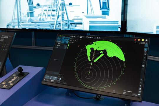Ship radar navigation display on a virtual bridge monitor showing green radar sweep, bearings, range rings and vessel targets used for marine traffic monitoring. Maritime simulation system equipment
