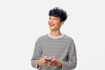 smiling man wearing striped shirt holding a smartphone, looking away cheerfully, short curly hair,...