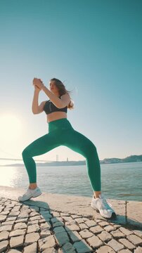 Athletic woman performing sumo squats outdoors