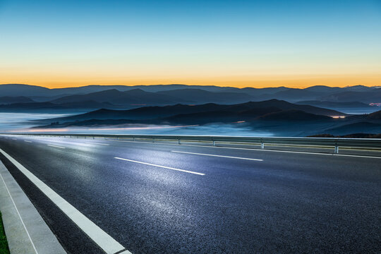 Modern high speed highway passing through foggy mountain landscape at twilight