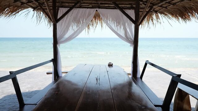 The dining table is decorated in a white seaside theme. The thatched roof is decorated with white curtains