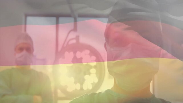 Animation of flag of germany over caucasian surgeons wearing face masks