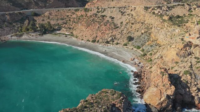 Drone perspective of the beautiful and secluded la rijana beach in granada, spain. Pristine turquoise water lapping on a tranquil shore