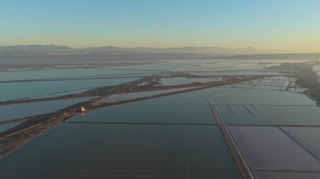 Majestic aerial view of the santa pola salt flats in spain during a colorful sunset. The vast water basins reflect the sky's light