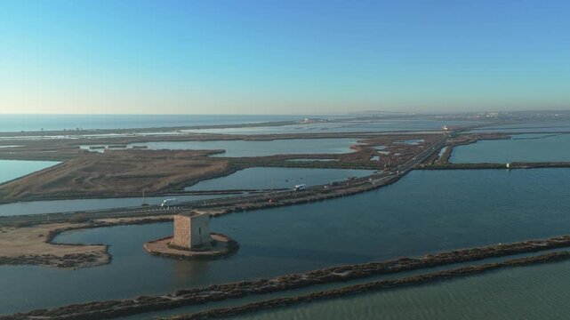 Beautiful aerial footage showing the historic tamarit tower surrounded by the salt lakes in santa pola, alicante, spain, at sunset