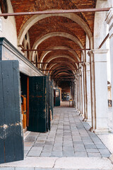 Naklejka premium Walking through an old arcade with arches and wooden doors in a historic town