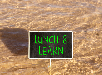 Naklejka premium Lunch and learn symbol. Concept words Lunch and learn on beautiful black blackboard. Beautiful Red sea water background. Business, educational and lunch and learn concept. Copy space.