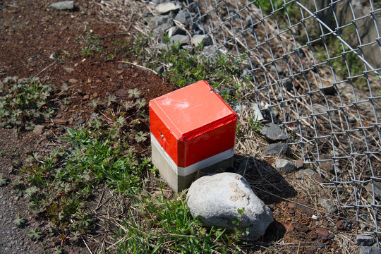 Red and white concrete boundary marker on ground