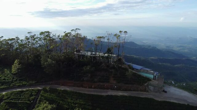 Cinematic drone shot showcasing Lipton&rsquo;s Seat viewpoint, Haputale, Sri Lanka, revealing scenic views of endless greenery, distant mountains, and clouds.