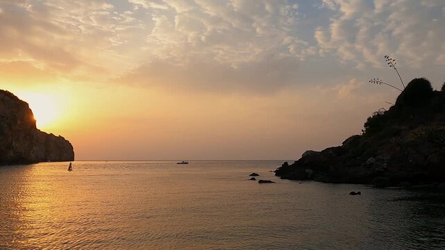 Peaceful sunset at Spiaggia Cala Rossa in Sicily, with a paddleboarder silhouetted against calm golden waters