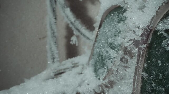 Frozen car mirror under heavy frost. Side mirror coated in dense ice crystals and rime, vintage green paint rimmed by granular snow, still silhouette evokes roadside abandonment and commuter memory,