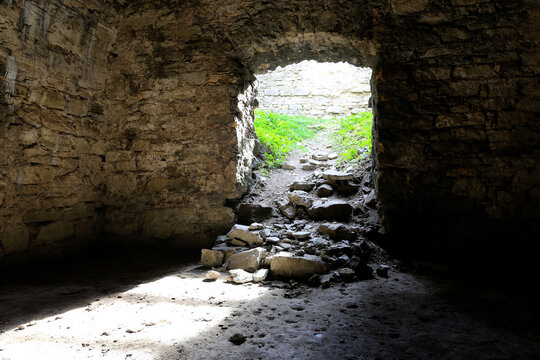 Stone archway leading from dark ruin to bright green overgrown path