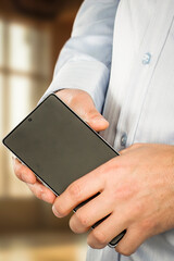 Businessman hands holding a smartphone, clean and neutral office background. Modern communication, digital business and mobile technology.