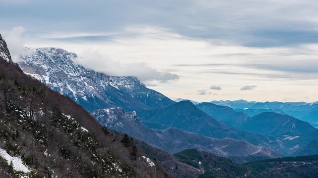 Timelapse of fog forming over mountain ridge and clouds drifting along Vercors slopes from Col du Rousset, France
