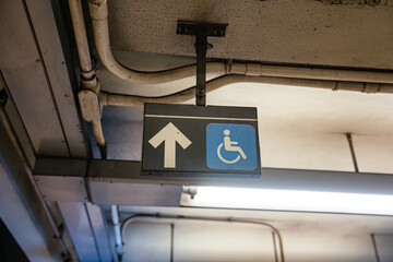 Accessibility sign with wheelchair symbol and upward arrow inside Broadway Lafayette Street subway station in Manhattan. Underground New York City metro environment showing public transportation and