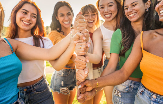Multicultural group of women stacking hands together - Female community concept with different girls support each other - Girlfriends hugging outdoors