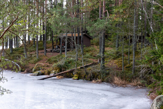 Windbreak and fire place near icy lake in forest