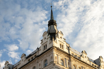 Towering roofline reaching into sky, urban details on ornate cornices and turrets, sunlight catching upper windows and casting crisp shadows © Alena