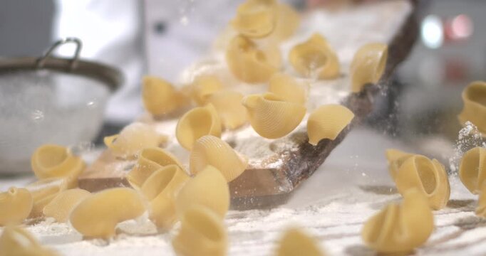 Making pasta in a busy kitchen with flour and shells on the countertop during a cooking session
