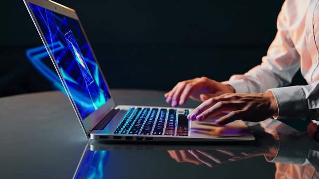 man at laptop typing on keyboard. screen displays animation under blue light. desk reflects device. technology creates modern workspace. hand and wrist align over keyboard. reflection boosts contrast.