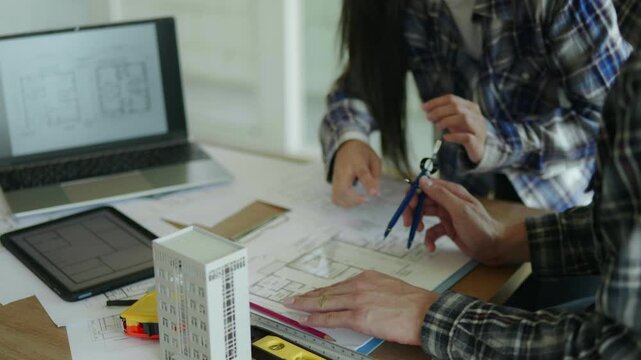 Architect and engineer working brainstorming and measuring for cost estimating on paperworks and floor plan drawings about design architectural and engineering for houses and buildings.