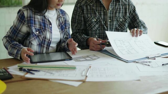 Architect and engineer working brainstorming and measuring for cost estimating on paperworks and floor plan drawings about design architectural and engineering for houses and buildings.