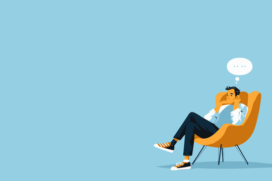 Contemplative young caucasian male relaxing in yellow chair against blue background