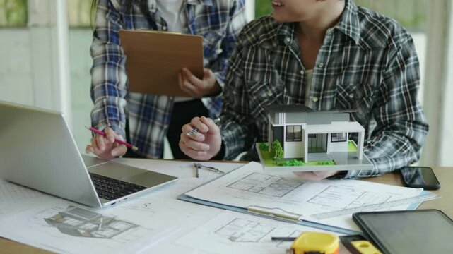 Architect and engineer working brainstorming and measuring for cost estimating on paperworks and floor plan drawings about design architectural and engineering for houses and buildings.