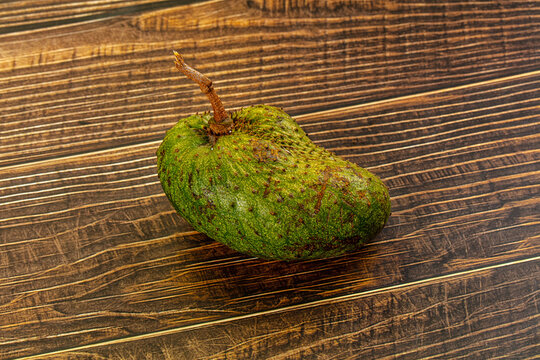 One whole raw soursop fruit, or graviola, isolated on a textured background.