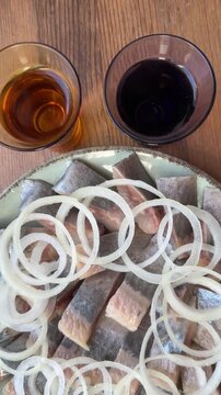 pickled herring with onion rings and two shots of vodka. a traditional appetizer shot in close-up. flatlay