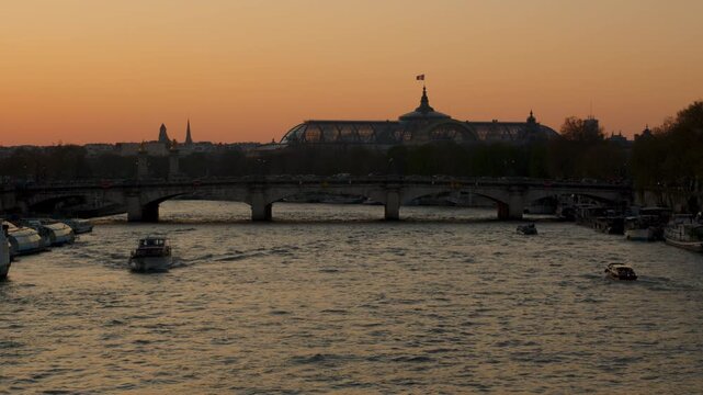 The Grand Palais and the river La Seine in Paris with the orange sky of sunset  