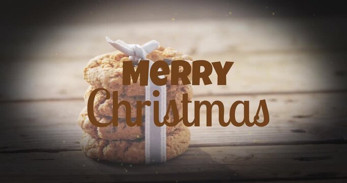 Animation of merry christmas text banner against close up of stack of cookies on wooden surface