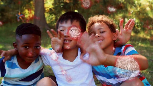 Three boys sitting on grass under tree, sparkles rising and causing hugging, waving for education