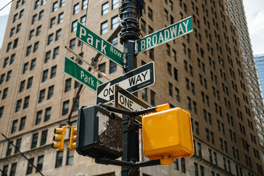 Close up of Broadway and Park Row street signs at a Manhattan intersection in New York City. Skyscrapers and office buildings form the background of the downtown financial district.